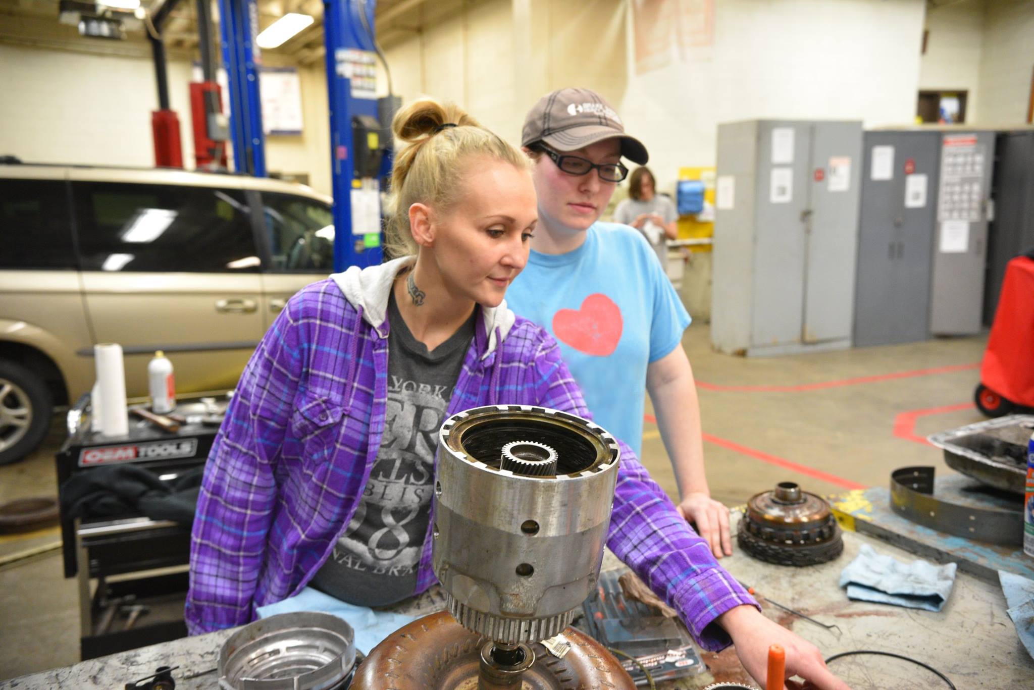 Two of our female Auto Tech students looking at an open car hood in our garage