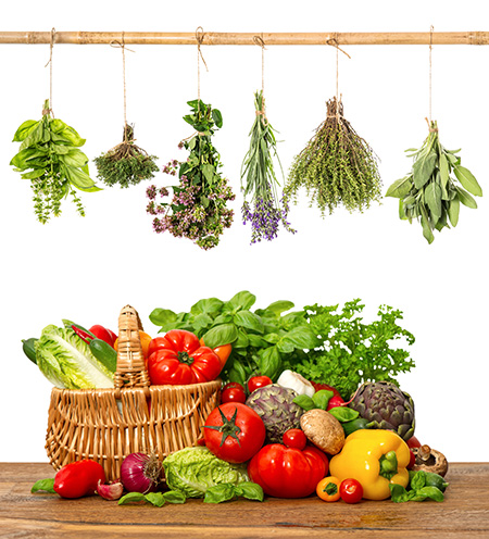 A selection of fresh vegies hanging from a bar and in a basket bellow them.
