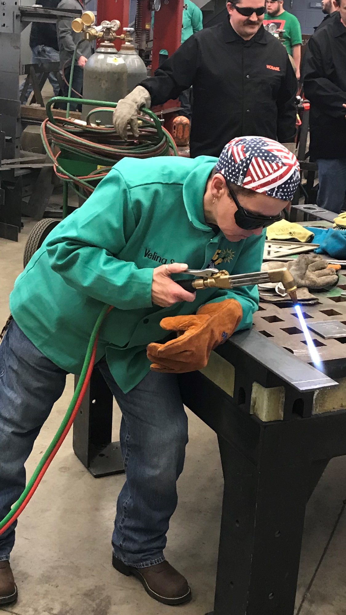 Velina Stacy welding in the lab while her classmates watch